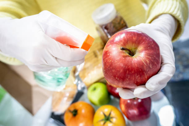 Close-up on a woman disinfecting an apple after going grocery shopping using an antibacterial spray and wearing gloves